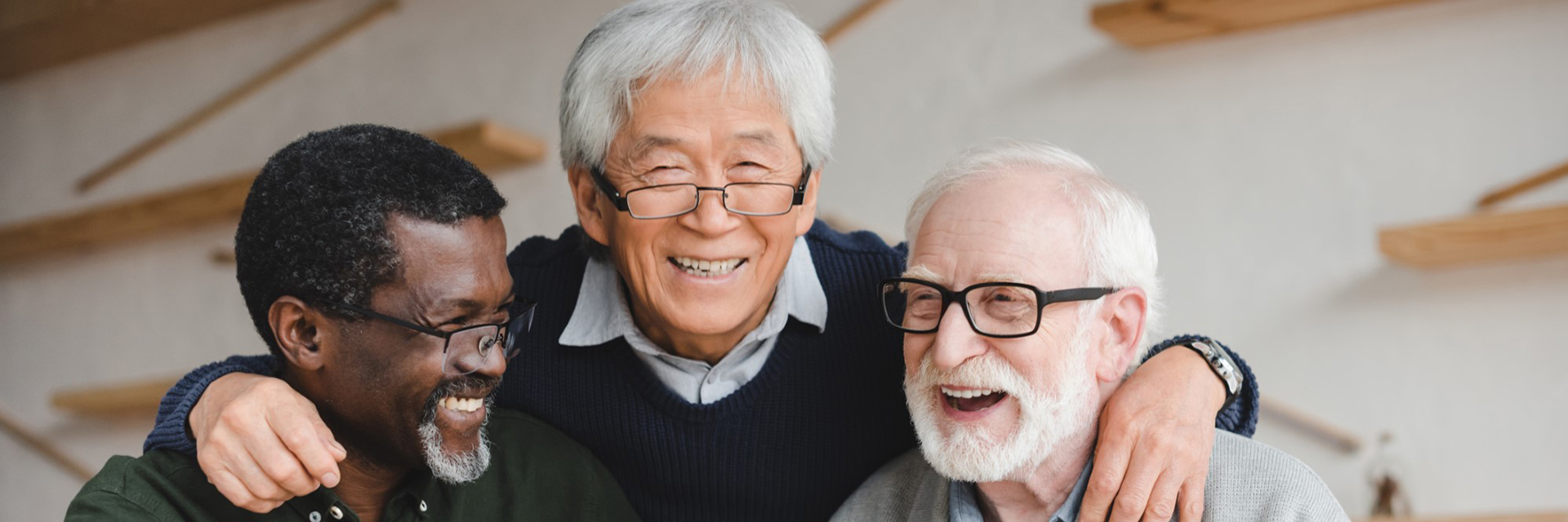three men in glasses smiling arms around each other
